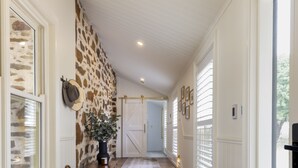 A hallway with a patterned rug, a stone wall, and a door at the end. - Merilli1885 - Private, Luxury Cottage (Currency Creek)