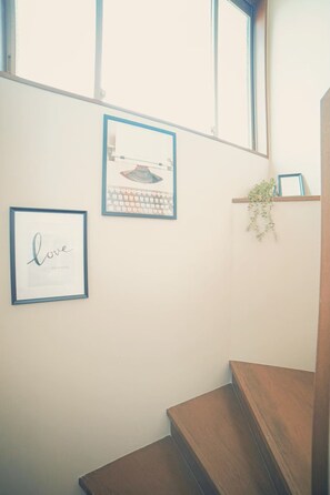 A staircase with wooden steps, a framed picture with the text "love yourself," and a small plant on a shelf.