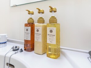 Three bottles of shower products on a bathroom counter. - Kochi Terminal Hotel (Kochi)