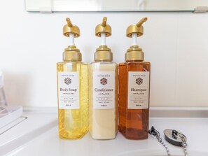 Three bottles of shower products on a bathroom counter. - Kochi Terminal Hotel (Kochi)