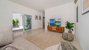 A modern living room with a sofa, a flat-screen TV, and a wooden cabinet. - Balinese-Style 2BR Pool Villa Aemy (Rawai)