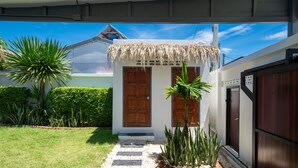 A house with a thatched roof entrance, a wooden door, and a small garden with white pebbles and plants. - Balinese-Style 2BR Pool Villa Aemy (Rawai)