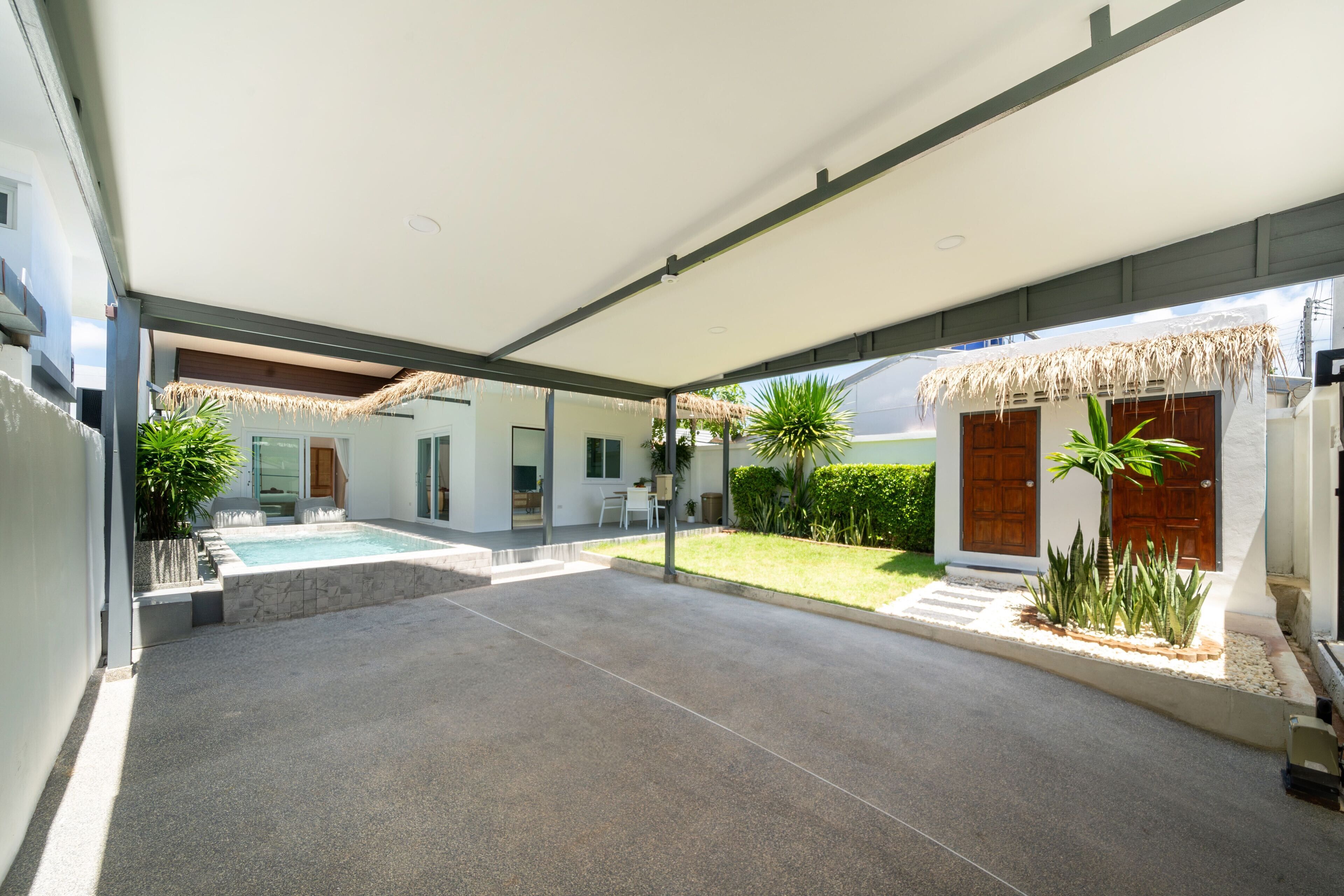 Een modern huis met een overdekte patio, een zwembad en een verzorgde tuin.