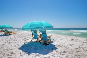 Beach chairs and umbrellas on a sandy beach with the ocean in the background. - Newly remodeled, beachfront with stunning views of the beach, pool and courtyard (Destin)