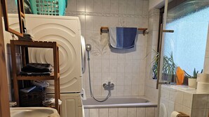 A compact bathroom with a toilet, sink, and shower. There are towels and a basket on a shelf. - **Charming feel-good oasis with sun terrace! Pet friendly**. (Brühl)