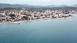 An aerial view of a coastal town with buildings along the shoreline and boats in the water. - Apartment Belu (Sibenik)