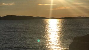 A sunset over a calm body of water with distant landforms. - Apartment Belu (Sibenik)