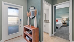 A hallway with a wooden console table, a mirror, and a door with frosted glass panels.