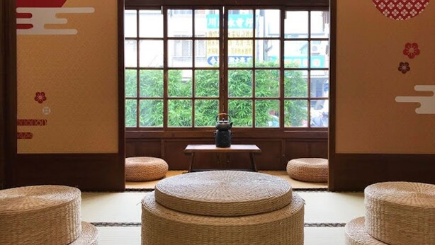 A traditional Japanese room with tatami mats, a low table, and a window with a view of greenery. - victory guesthouse (Pingtung)