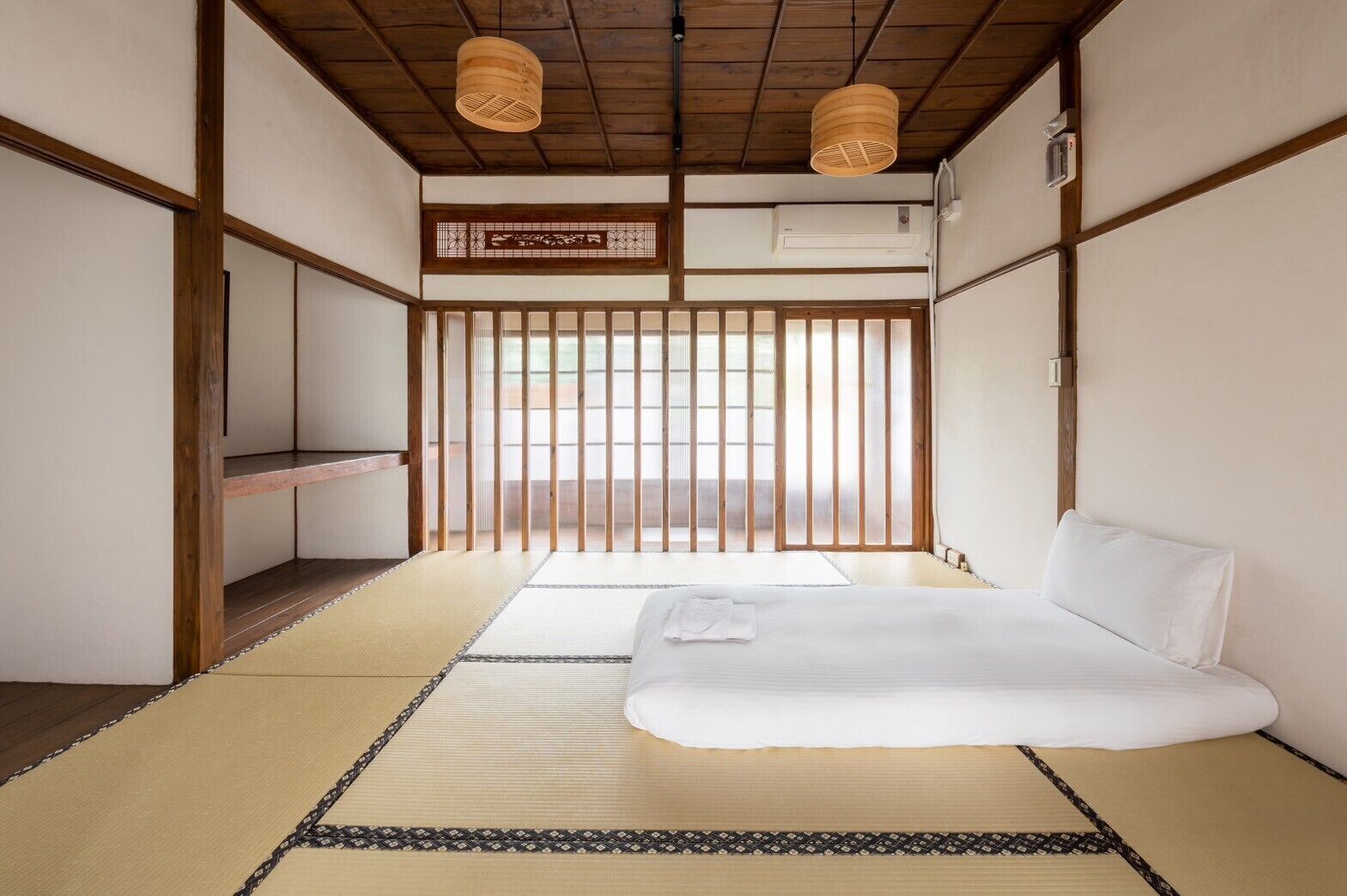 A traditional Japanese room with tatami flooring, a low bed, and sliding doors.