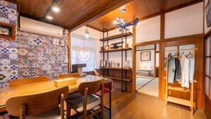 A traditional Japanese-style room with tatami flooring, a low wooden table with chairs, a bookshelf, and a clothing rack. - victory guesthouse (Pingtung)