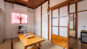 Une pièce de style japonais traditionnel, avec un sol recouvert de tatamis, une table en bois, un coin pour préparer le thé et des portes coulissantes.