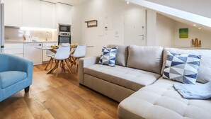 Un apartamento moderno con comedor, kitchenette y sala de estar con sofá y sillones.
