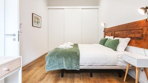 Un dormitorio con cama, mesita de noche y cabecero de madera.