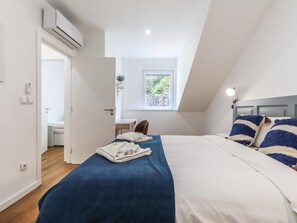 A bedroom with a bed, a desk, and a window.