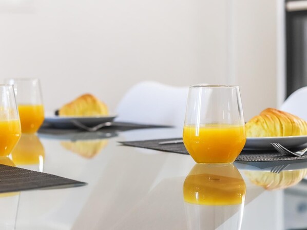 Una mesa de desayuno con dos vasos de jugo de naranja, un croissant y un plato de comida.