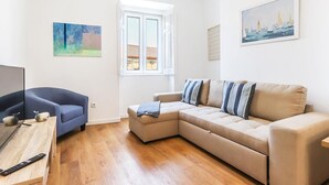 En moderne stue med sofa, blå lænestol, sofabord i træ og tv.
