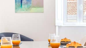 Et morgenbord med appelsinjuiceglas, croissanter og et fad med kager.