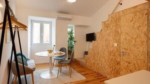 A room with a round dining table, two chairs, a hanging light fixture, and a wooden wall panel.