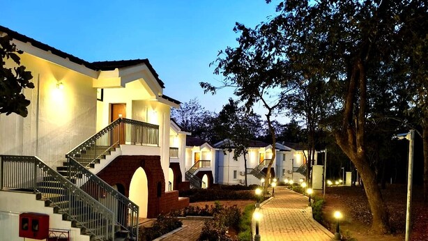A hotel with a central staircase, multiple balconies, and a paved pathway. - Amritara Serenity (Sanguem)