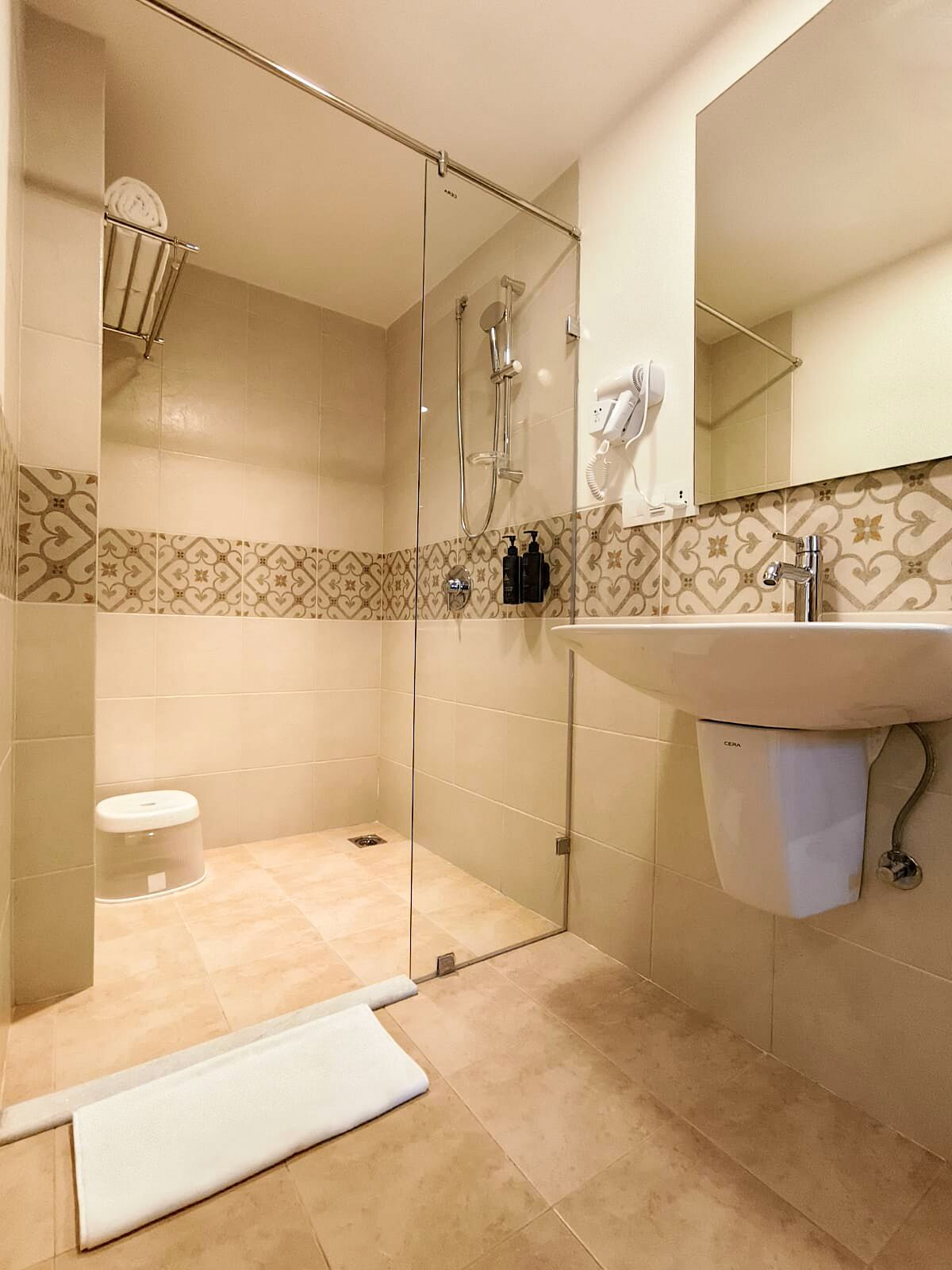 A modern bathroom with a glass-enclosed shower, a sink with a mirror, and patterned tiles.