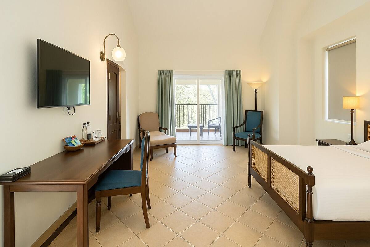 A hotel room with a bed, a desk, a chair, a television, and a balcony with a view.