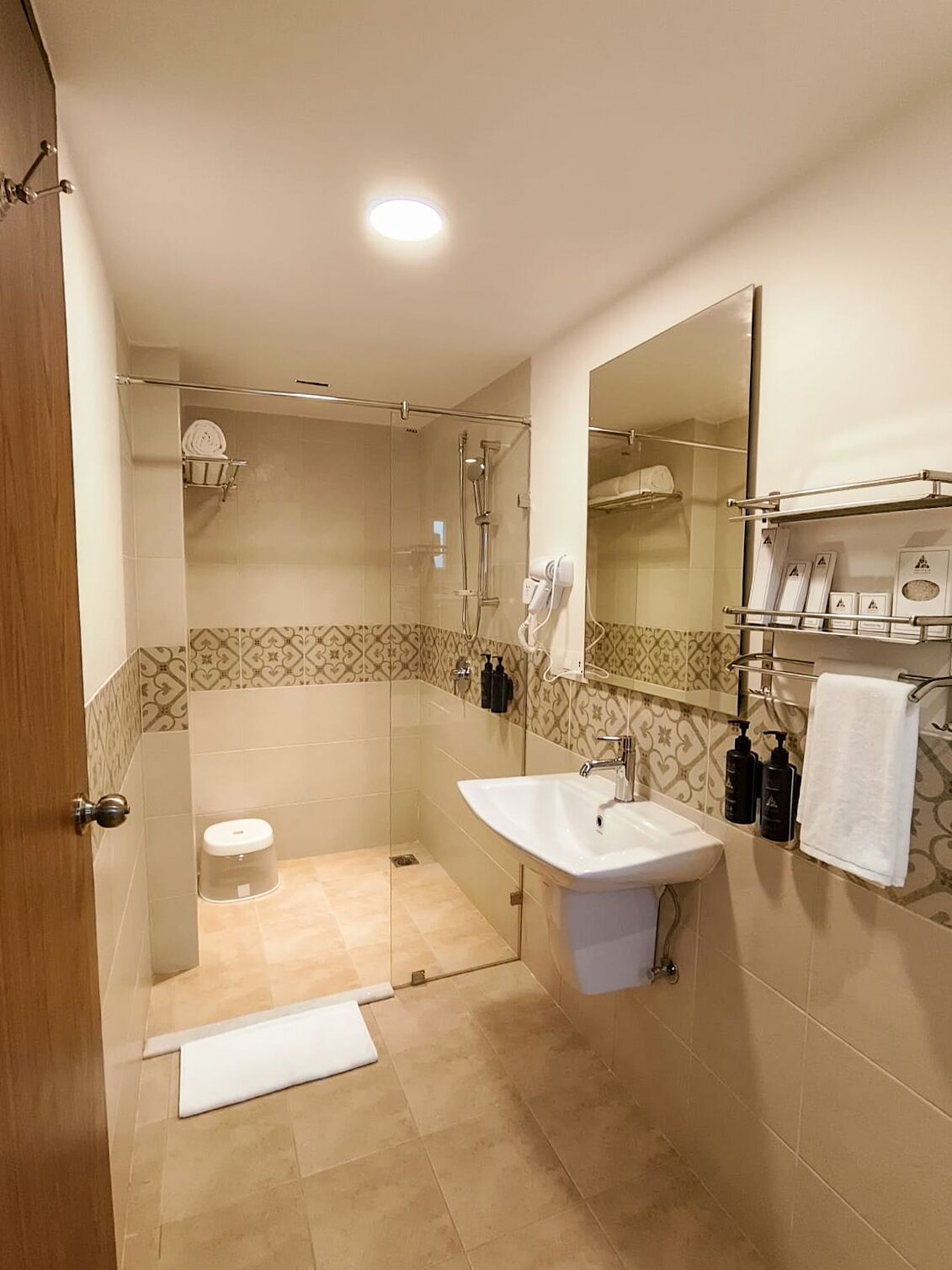 Een moderne badkamer met een douchecabine van glas, een witte wastafel en een grote spiegel.