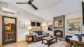 Un salon doté d’une cheminée, d’un ventilateur de plafond et d’un coin repas avec une table et des chaises.