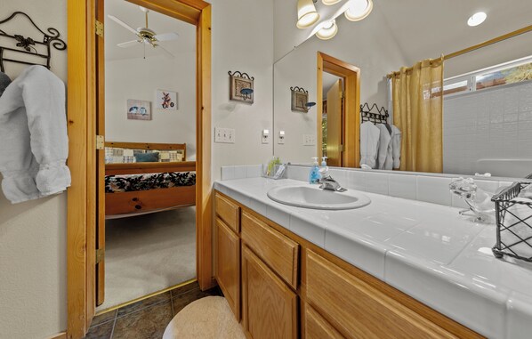 A bathroom with a white sink, wooden cabinets, a mirror, and a shower curtain.