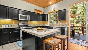 A modern kitchen with dark cabinets, a granite countertop, and a central island with stools.