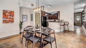 Una cocina moderna con armarios de madera oscura, una isla central con taburetes y una zona de comedor con una mesa y sillas oscuras.