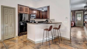 Una cocina moderna con armarios de madera oscura, un refrigerador de acero inoxidable, un microondas y una isla grande con taburetes de bar.
