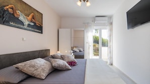 A bedroom with a bed, pillows, a painting, a TV, and a view of the outdoors. - Apartment Tafra 2 (Omis)