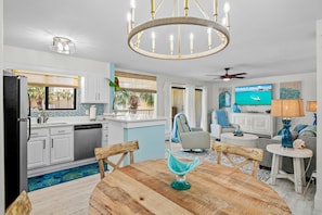 Een moderne keuken met witte kasten, een zwarte koelkast en een eethoek met een houten tafel en stoelen.