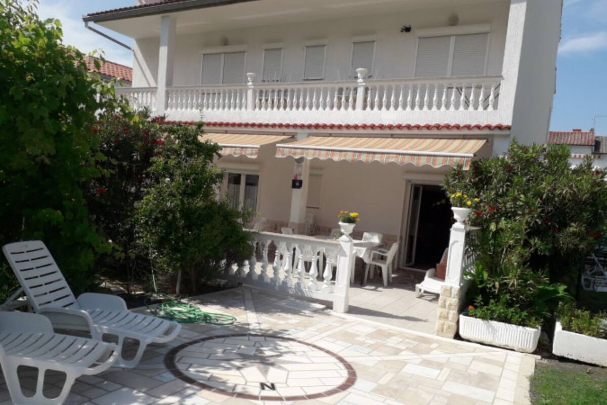 A two-story building with a covered patio area, outdoor seating, and a garden.