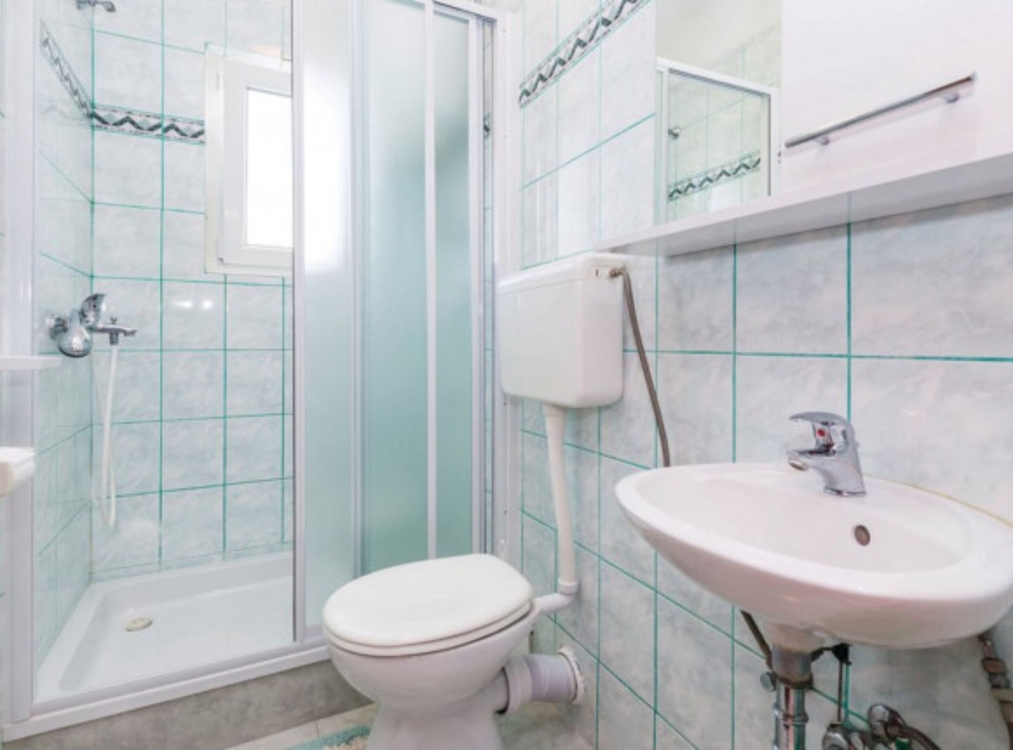 A bathroom with a glass shower enclosure, a toilet, and a sink.