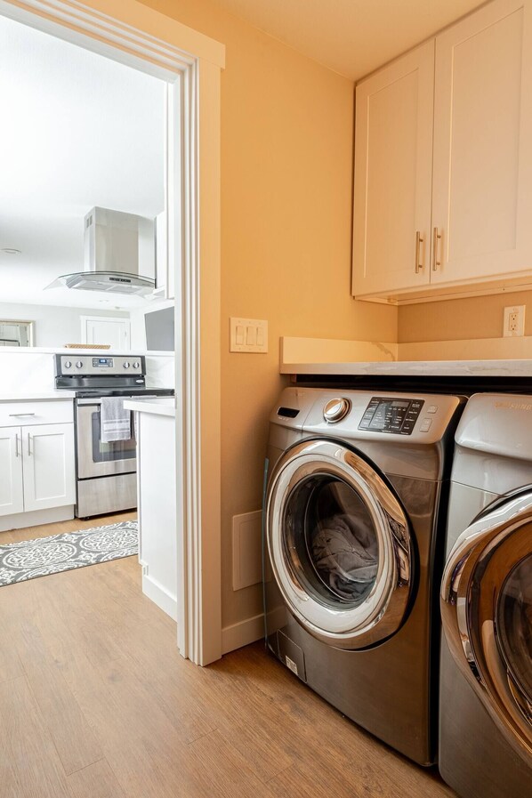 A modern kitchen with white cabinets, stainless steel appliances, and a built-in oven.