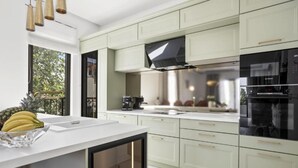Een moderne keuken met lichtgroene kastjes, een groot kookeiland met spoelbak en een inbouwoven.