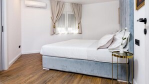 Een slaapkamer met een bed, een rond nachtkastje, een schilderij en een airconditioner.