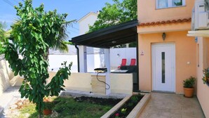 A residential building with a covered outdoor seating area, a small garden, and a door with a sign. - Holiday Home Mumy (Dobrinj)