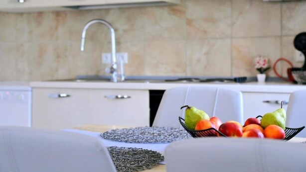 A modern kitchen with a sink, countertop, and a fruit bowl containing pears and apples. - Holiday Home Mumy (Dobrinj)