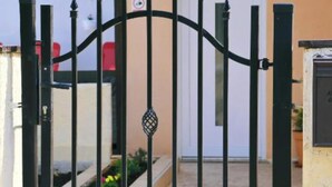 A gated entrance with a metal gate, a door, and a small garden area with flowers. - Holiday Home Mumy (Dobrinj)
