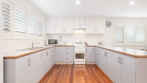 Eine Küche mit weißen Schränken, einer Mikrowelle, einem Toaster und einer Uhr an der Wand.