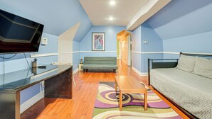 Una habitación con una cama, televisión, sofá y escritorio.