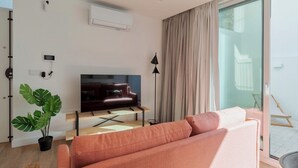 A modern living room with a flat-screen TV, a sofa, a plant, and a sliding glass door to a balcony. - Simple Life I, Setúbal (Setúbal)
