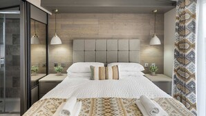 Una habitación de hotel moderna con una cama grande, dos mesitas de noche y un cabecero.