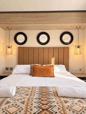 Un lit bien fait, agrémenté d’un tapis à motifs, d’une tête de lit en bois et de décorations circulaires fixées au mur.