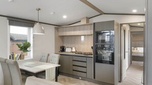 Una cocina compacta con electrodomésticos modernos, un comedor con mesa y sillas, y vistas al exterior a través de una ventana.