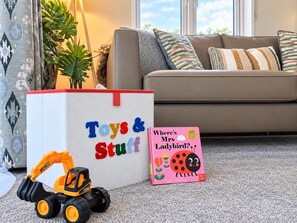 A living room with a sofa, a toy excavator, a gift bag, and a children's book.