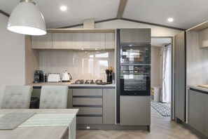 Una cucina moderna con forno a incasso e microonde, zona pranzo con tavolo e sedie, e un'ampia finestra che garantisce luce naturale.